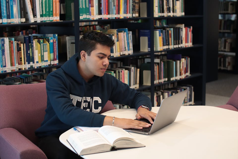 Student lernt mit Laptop in der Bibliothek, Berufsunfähigkeitsversicherung für Studenten