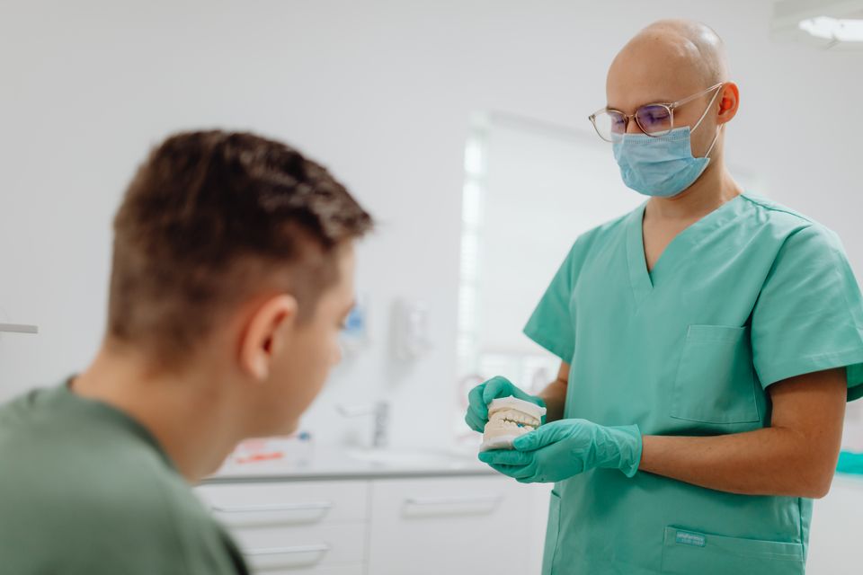 Zahnarzt erklärt einem Patienten am Zahnmodell die Regelversorgung und den sinkenden Festzuschuss für Zahnersatz ab 2027